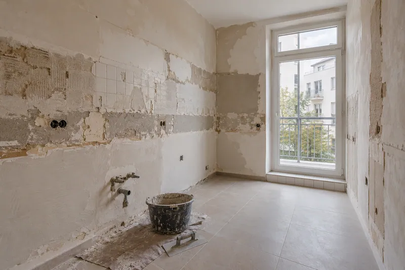 Visualización conceptual IA: Cocina sin muebles con paredes en preparación y zonas de enlucido.